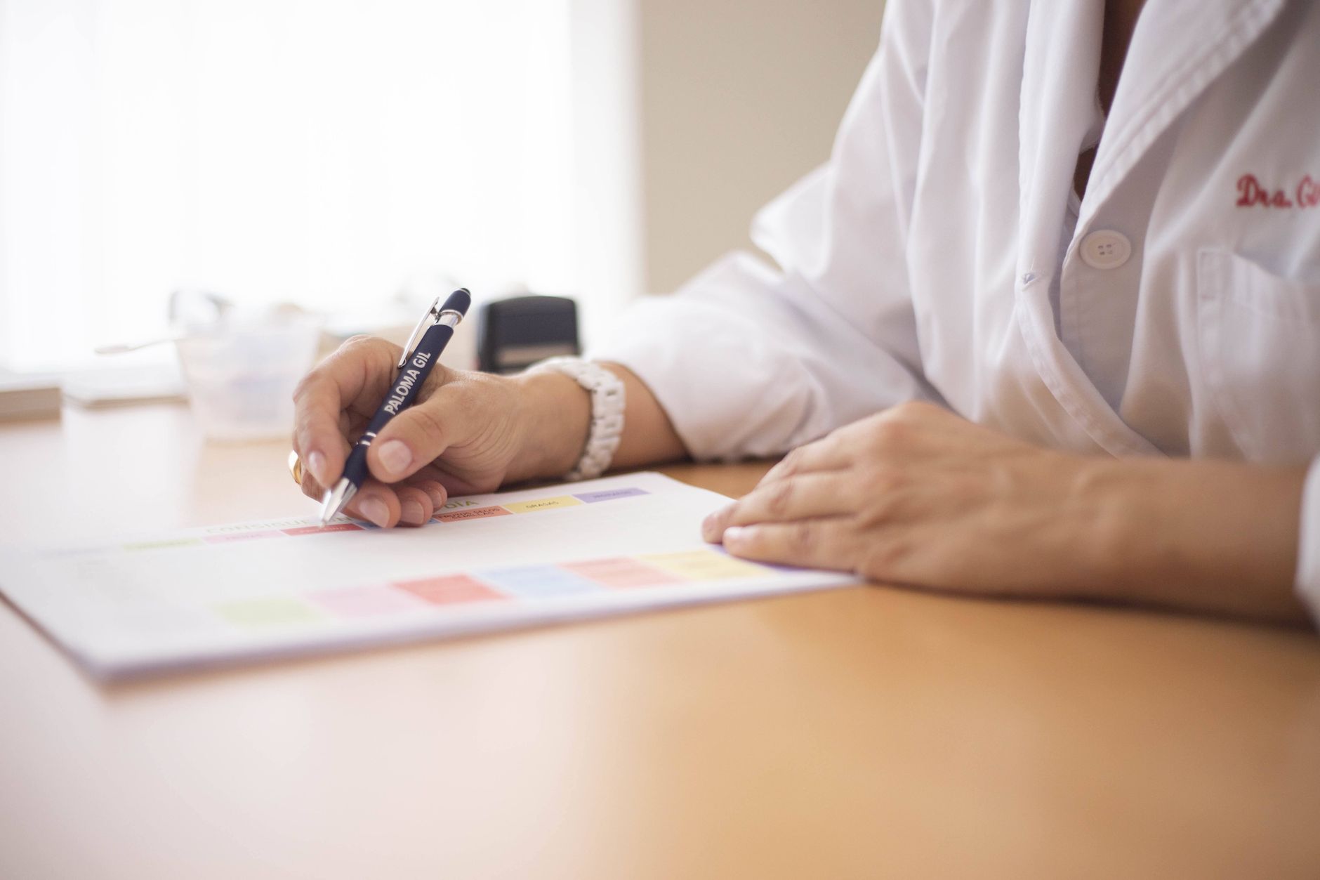 close up of a doctor sitting at a desk and writing on paper